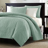 A bed adorned with a mint green comforter and matching pillows, creating a fresh and inviting atmosphere.